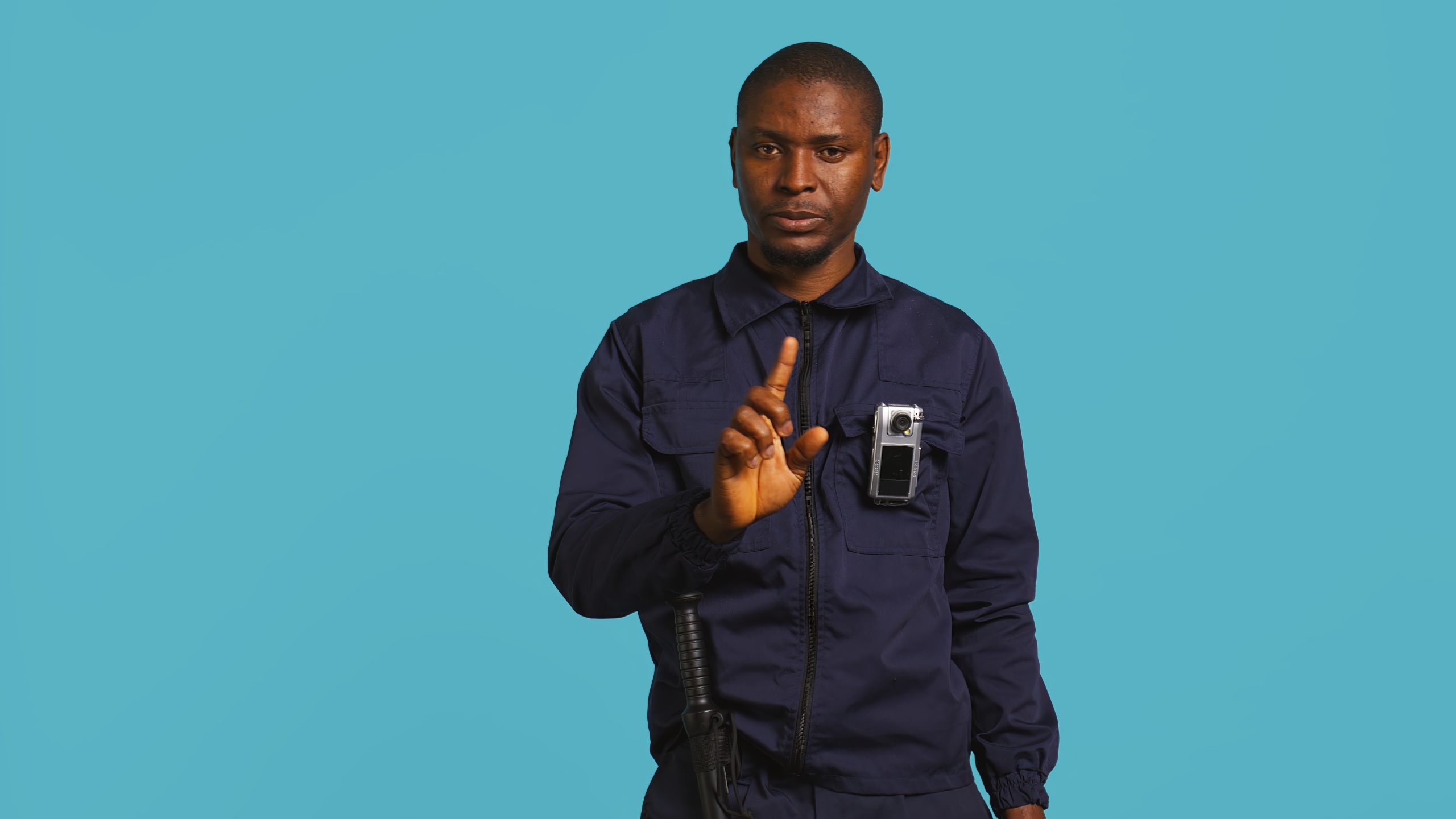 Portrait of menacing bodyguard pointing towards security body camera